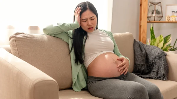 Vrouw heeft last van zwangerschapsmisselijkheid op de bank