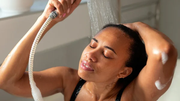 Vrouw zit in bad onder de douche, kan ze het water uit de douche drinken