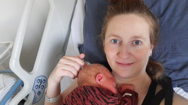 Marjolein had twee keer kraamvrouwenkoorts: 'Het kan je je leven kosten' Glimlachende vrouw ligt met haar baby op bed.