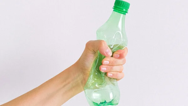 Een plastic flesje in een hand | plastic deeltjes in flessenwater