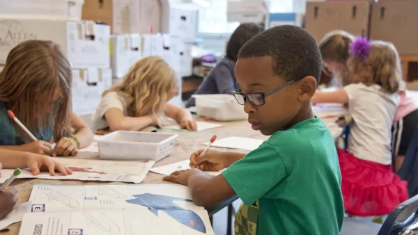 Een zwarte jongen in een klaslokaal met vooral witte kinderen | Ter illustratie bij discriminatie bij schooladviezen