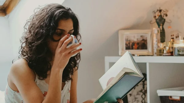 Vrouw leest boek en drinkt uit kopje