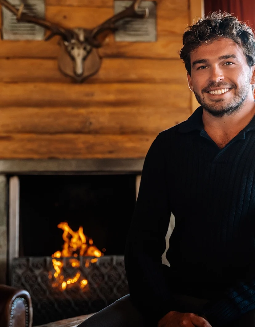 Benjamin in een zwarte trui bij een haardvuur