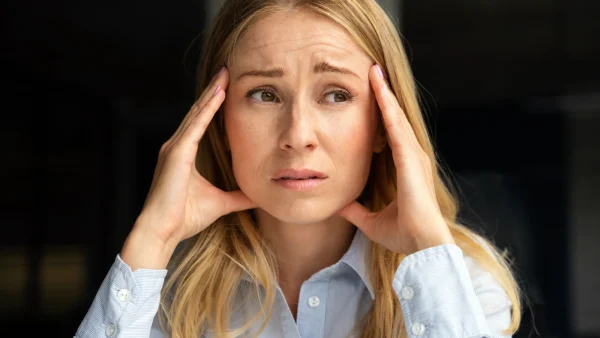 Vrouw, Elodie, zit met haar handen op haar gezicht en is gefrustreerd