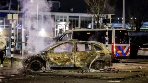 Een in brand gestoken auto tijdens de rellen bij een zalencentrum in Den Haag