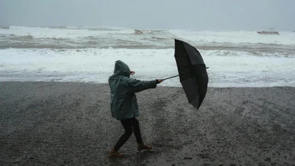 Storm Louis op komst, vrouw met paraplu in regen