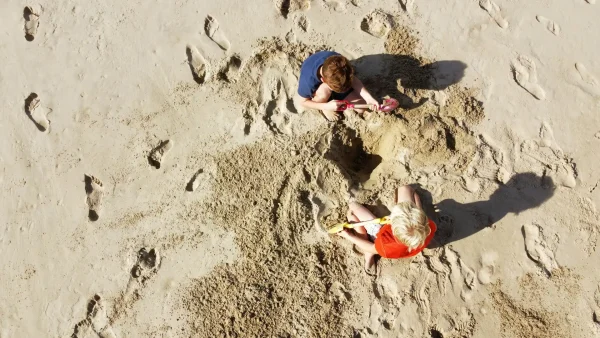Bovenaanzicht van kinderen die een kuil graven op het strand, ter illustratie