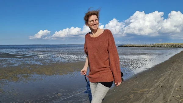 Lachende vrouw loopt over het strand: Grian vangt crisiskinderen op