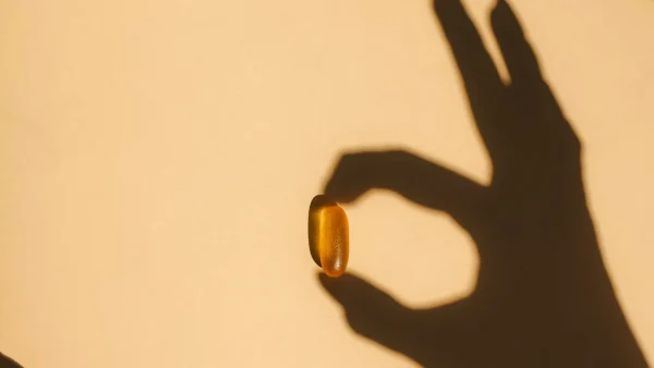 Schaduw hand houdt vitamine D pil vast
