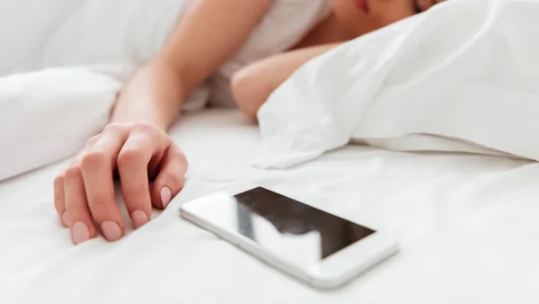 Vrouw ligt slapend in bed met telefoon naast haar