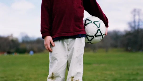 Jongen houdt bal vast op grasveld