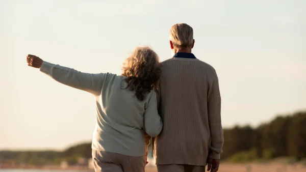 Oud koppel loopt samen op het strand
