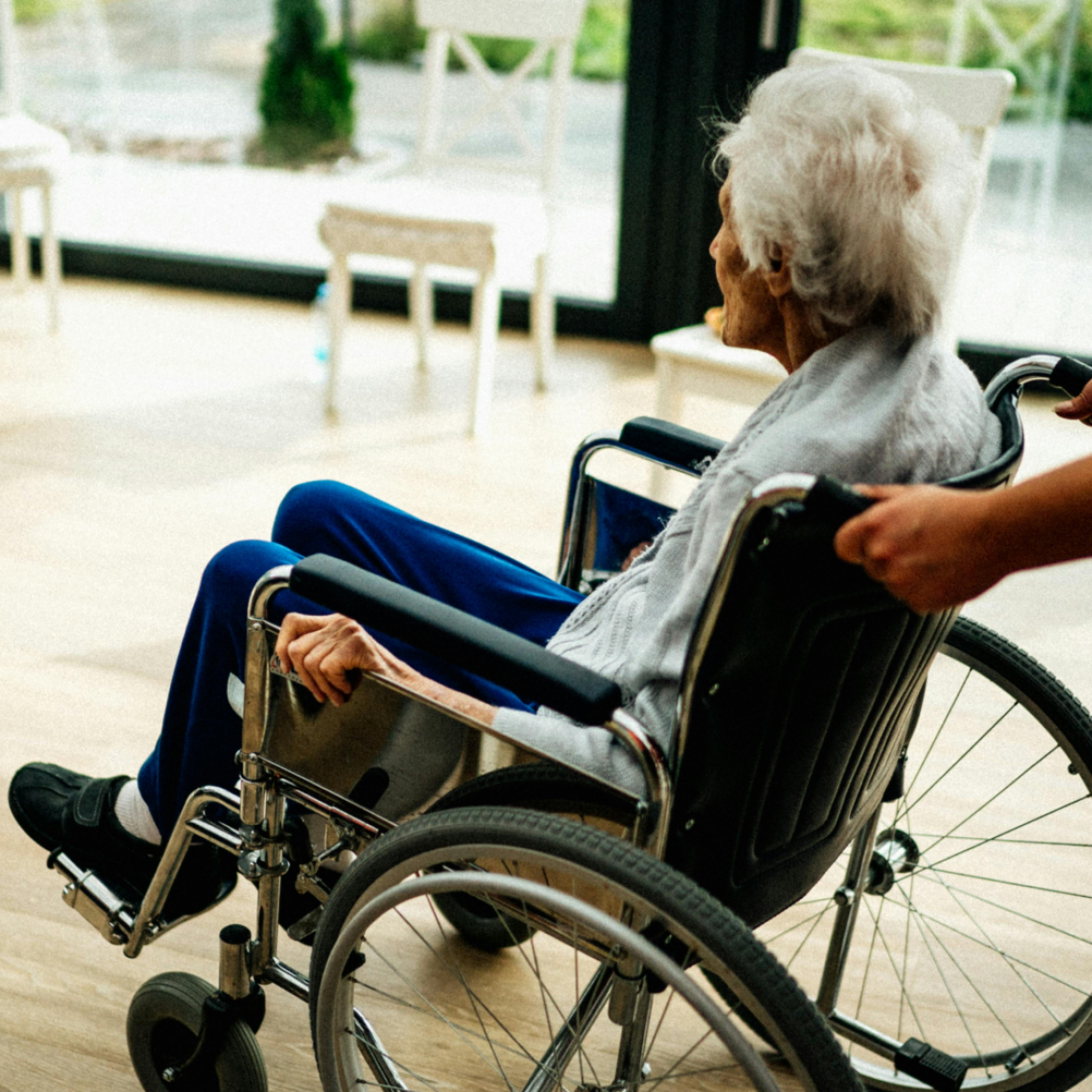 Vrouw in rolstoel wordt voortgeduwd mantelzorg