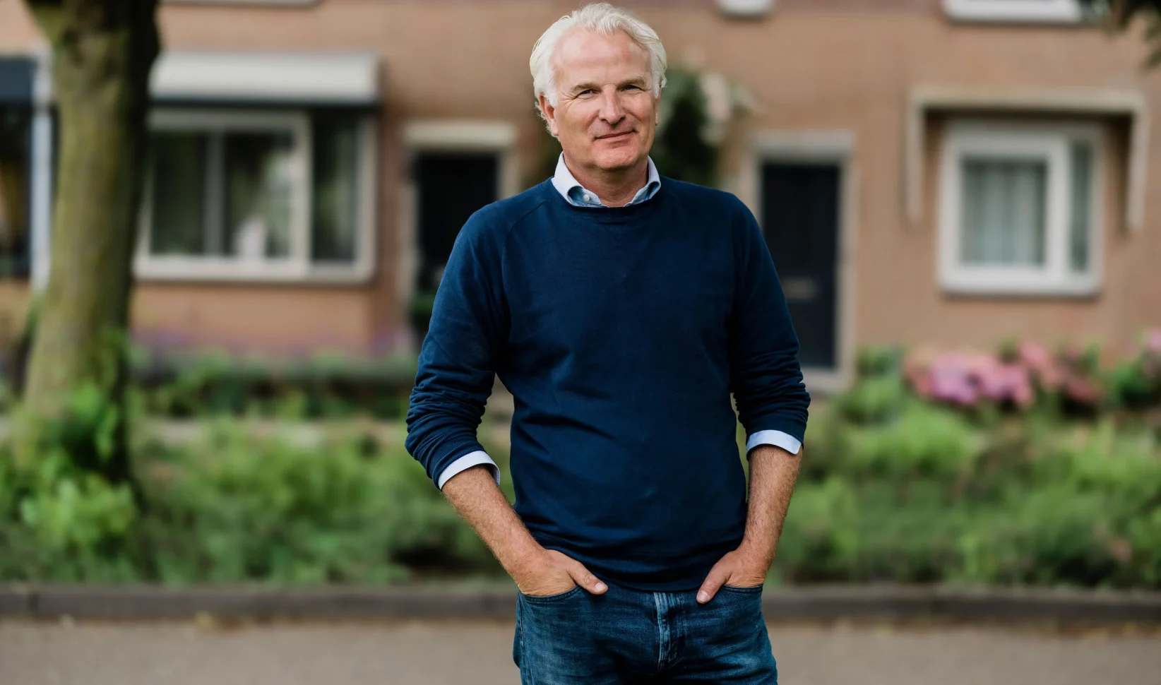 bob sikkes in donkerblauwe trui op straat voor een woning