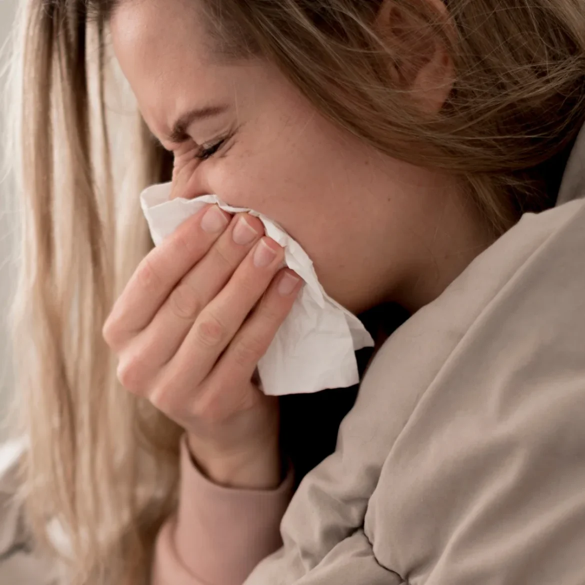 Vrouw met griep snuit haar neus in bed