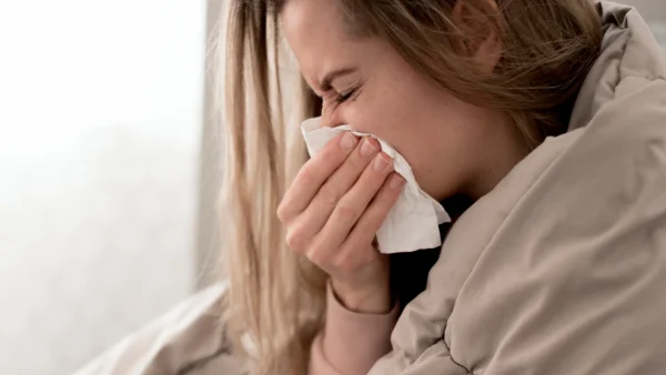 Vrouw met griep snuit haar neus in bed