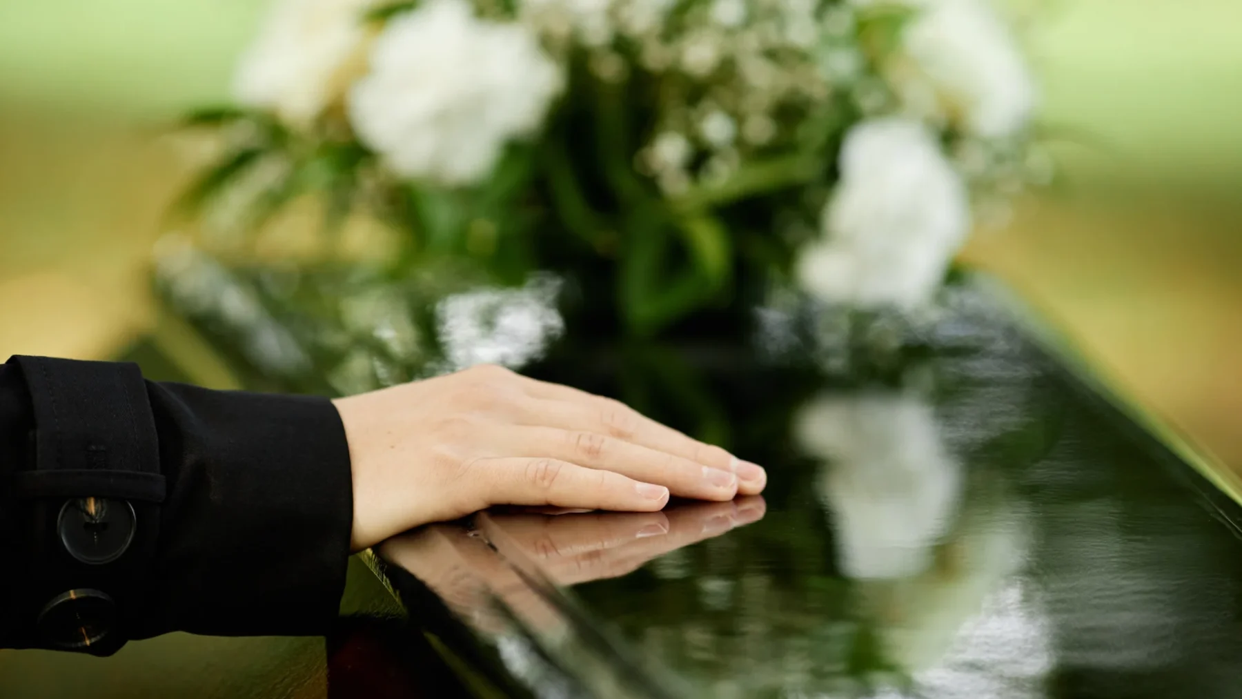 Vrouw houdt hand op kist voor een crematie