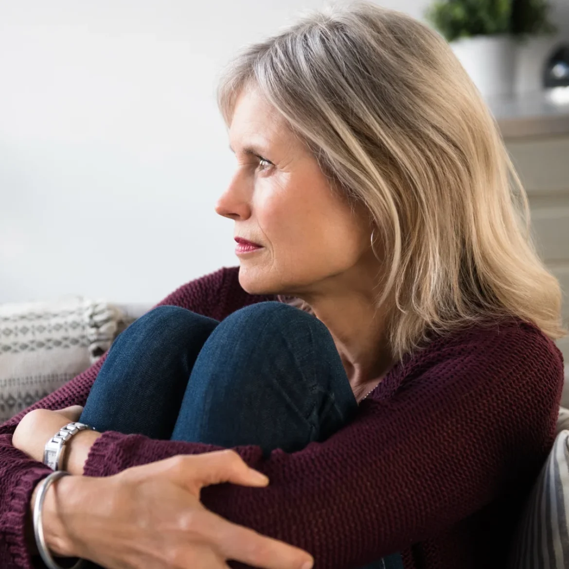 Vrouw, Aila, zit verdrietig op de bank om haar stiefdochter