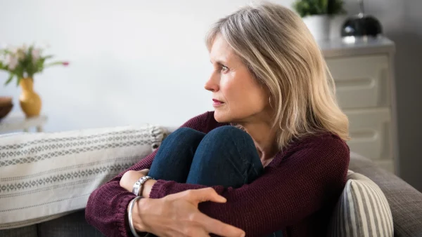 Vrouw, Aila, zit verdrietig op de bank om haar stiefdochter