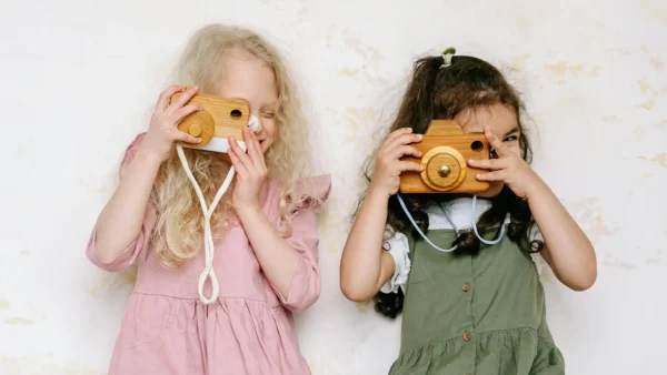 Twee kleine meisjes met een houten fotocamera