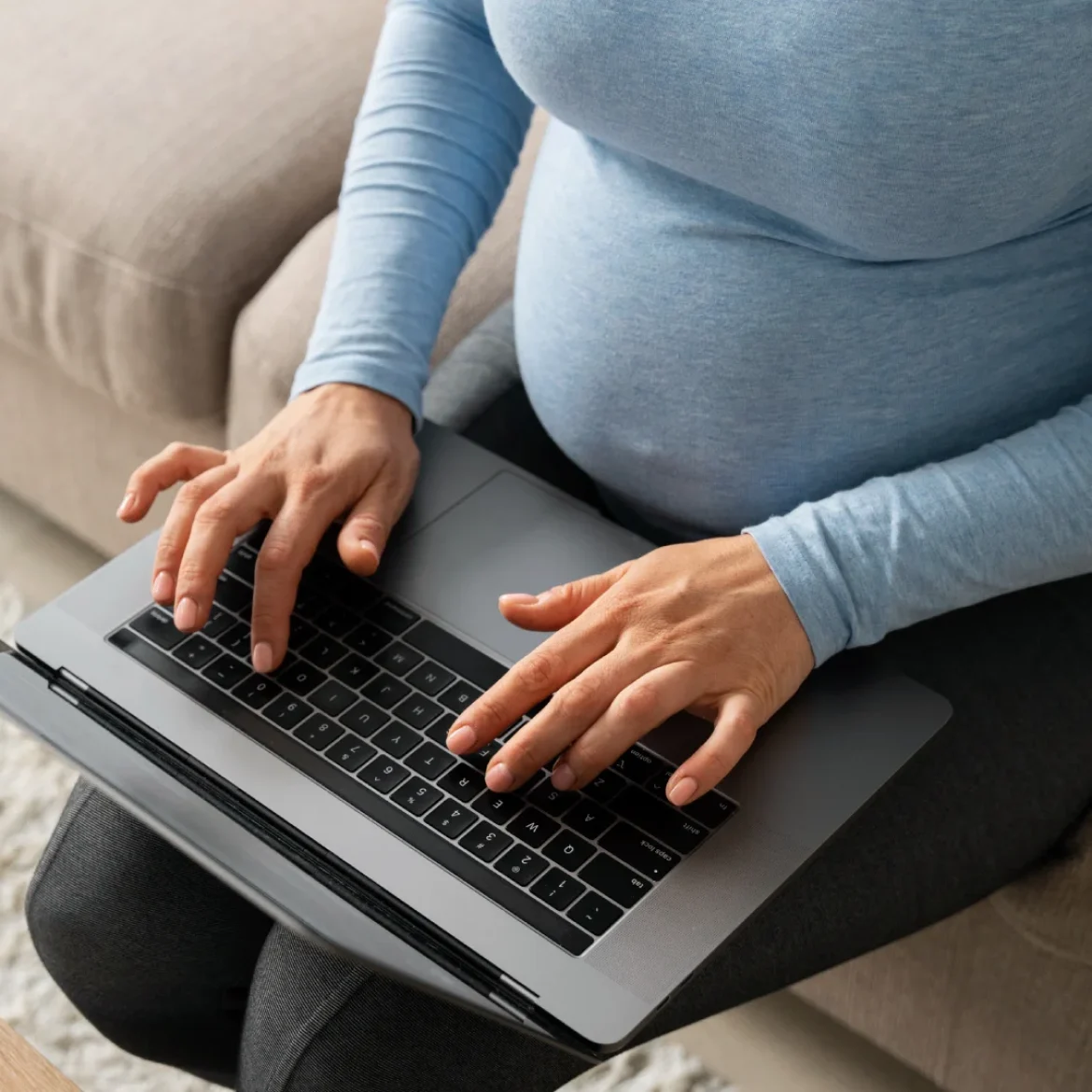 Zwangere vrouw typt op haar laptop en ervaart zwangerschapsdiscriminatie op de werkvloer