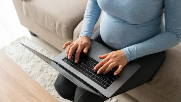 Zwangere vrouw typt op haar laptop en ervaart zwangerschapsdiscriminatie op de werkvloer