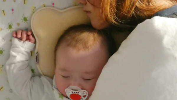 Parent sleeping with baby in bed