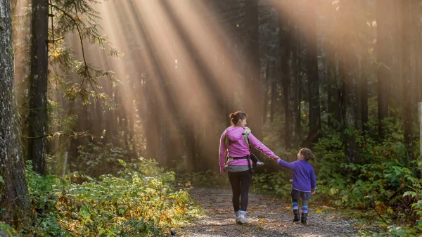 Vrouw met kind in bos met zonnestralen weer met pinksteren