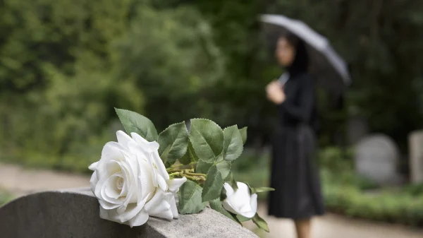 Roos op grafsteen van vader met vrouw erachter