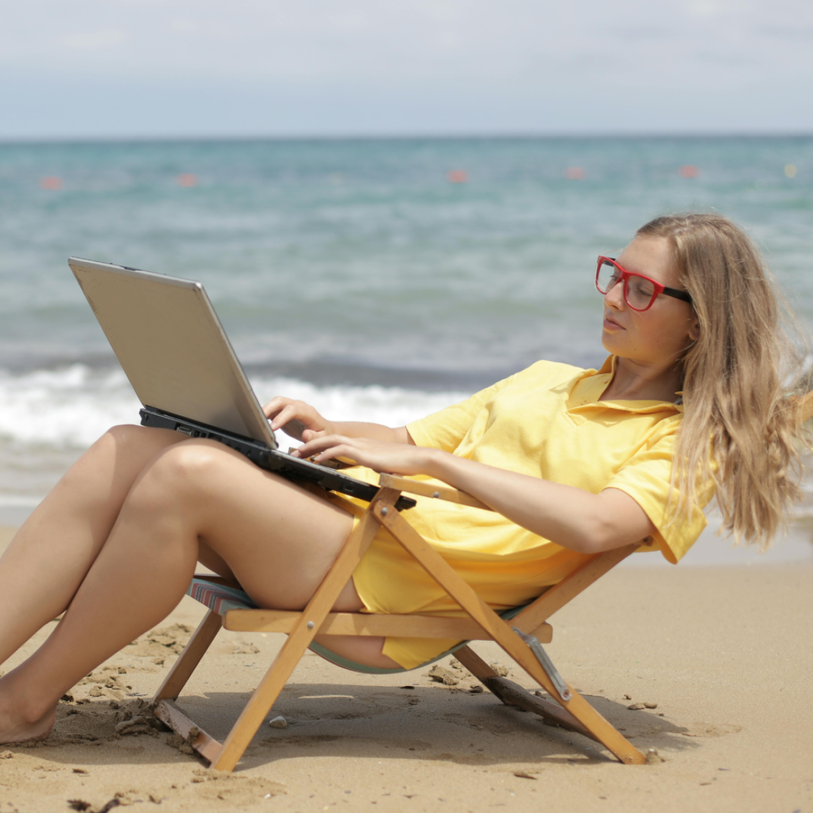 Vrouw met laptop werkend op een strand