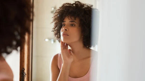 Vrouw kijkt naar huid in spiegel