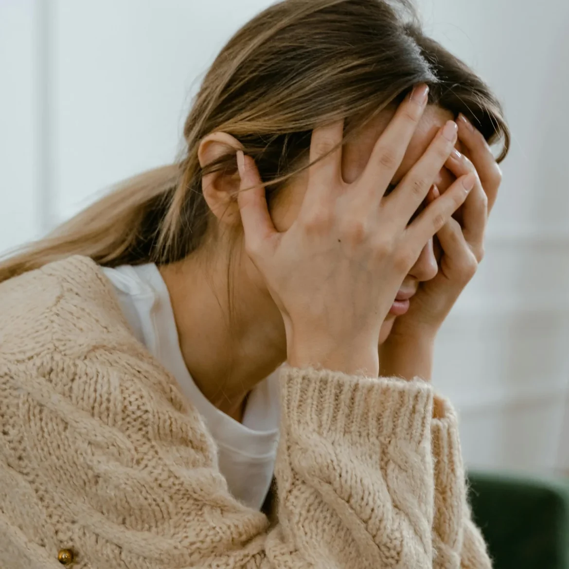 Vrouw zit met handen voor het gezicht