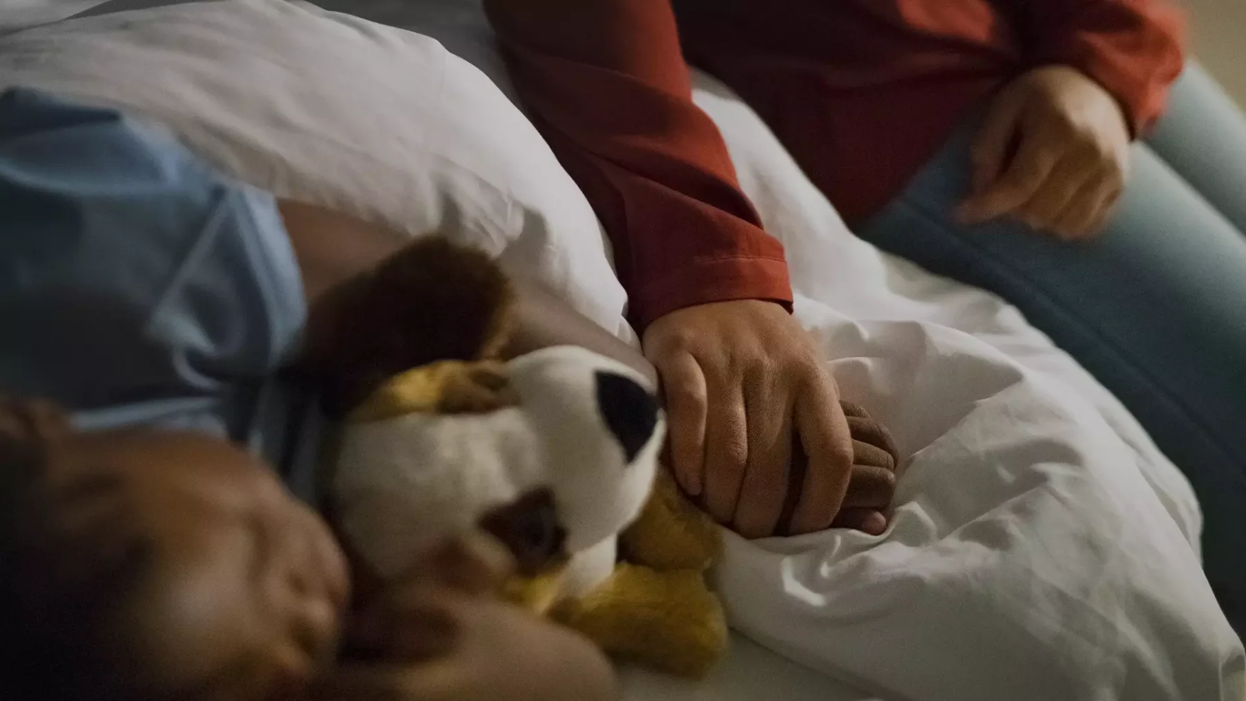 Vrouw houdt hand van slapend kind vast