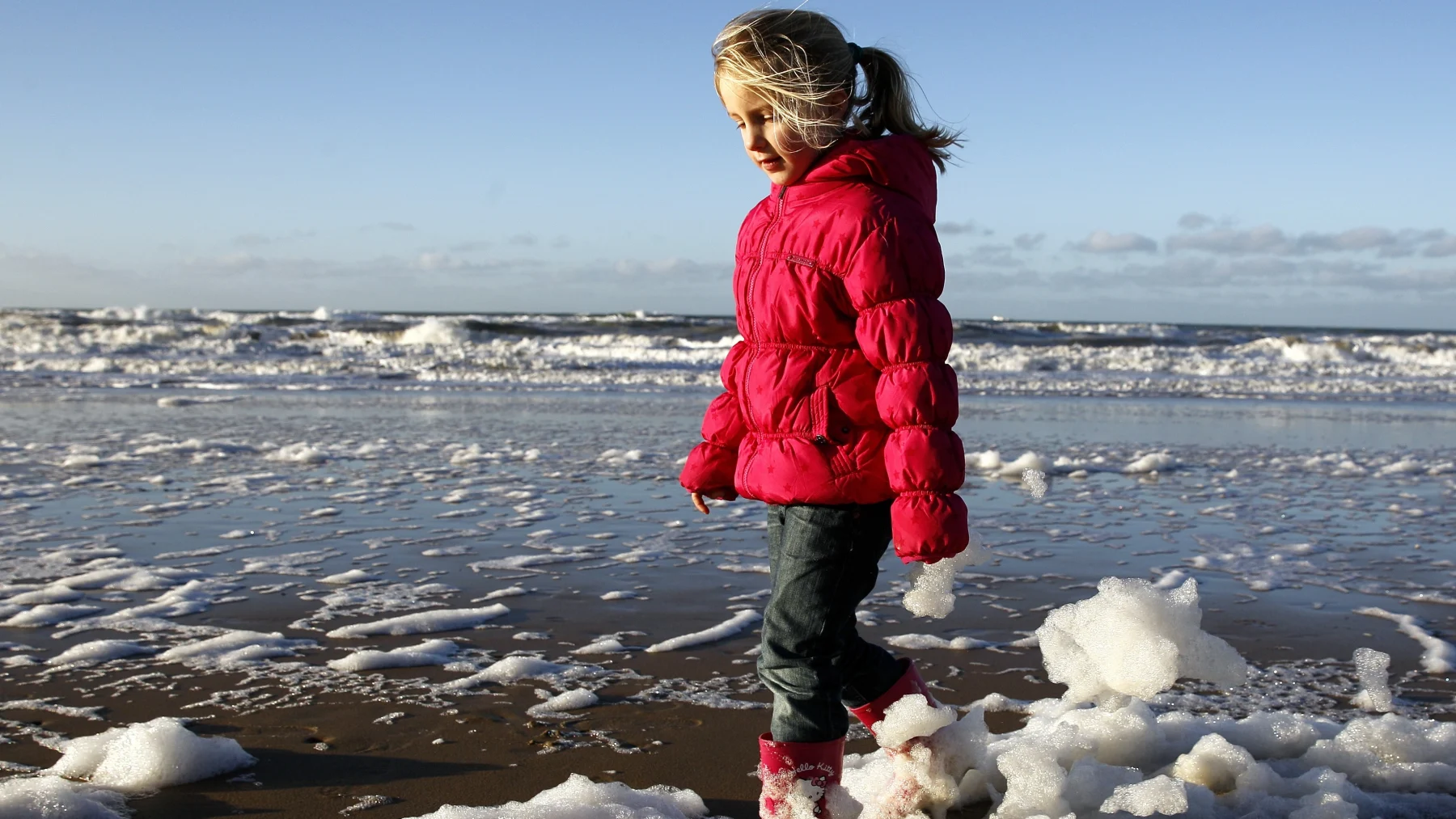Kind op een strand met zeeschuim