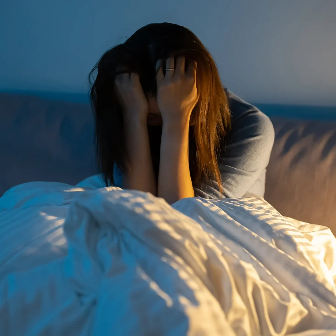 Vrouw in bed met handen voor haar gezicht