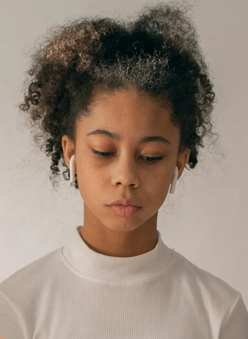 Kind met oortjes in en wijzende handen om haar heen