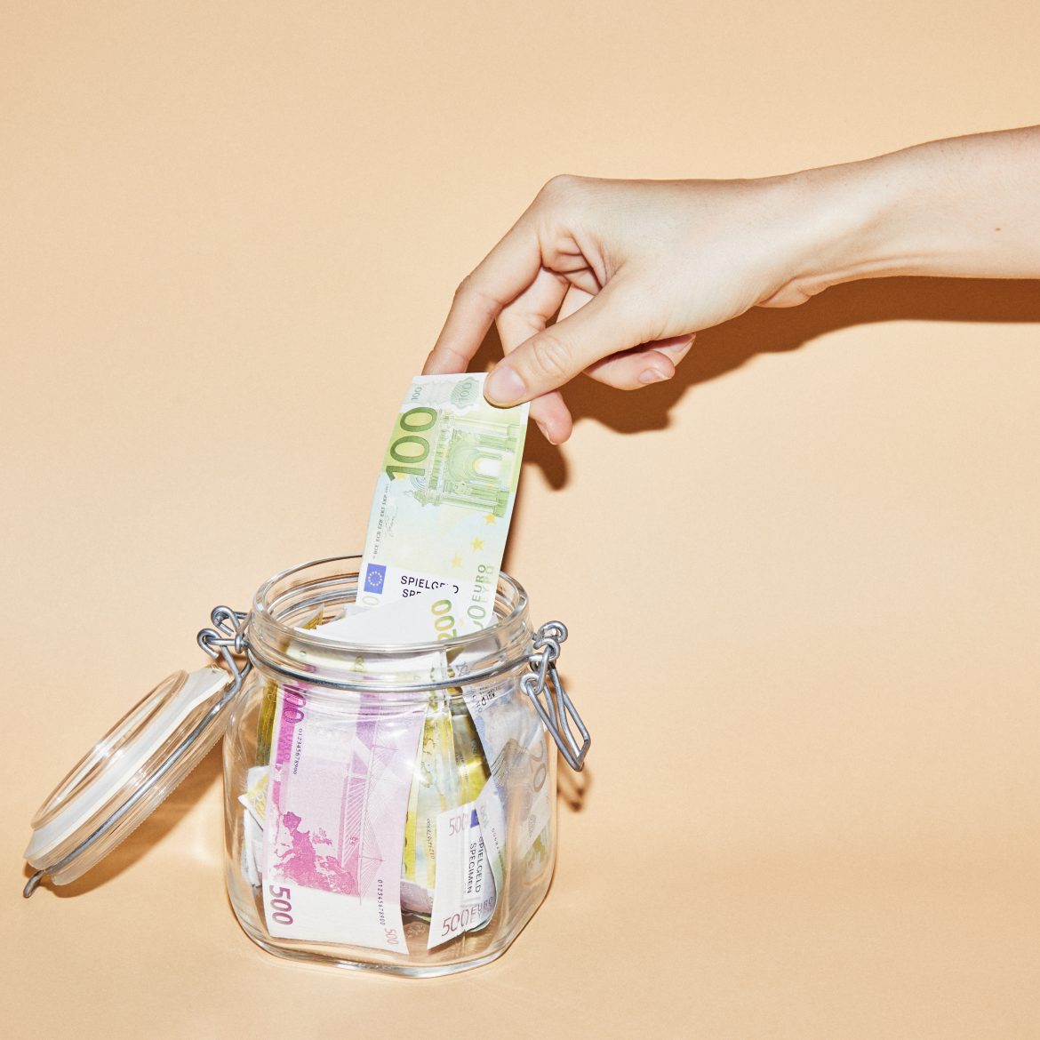 Hand pakt geld uit een spaarpot