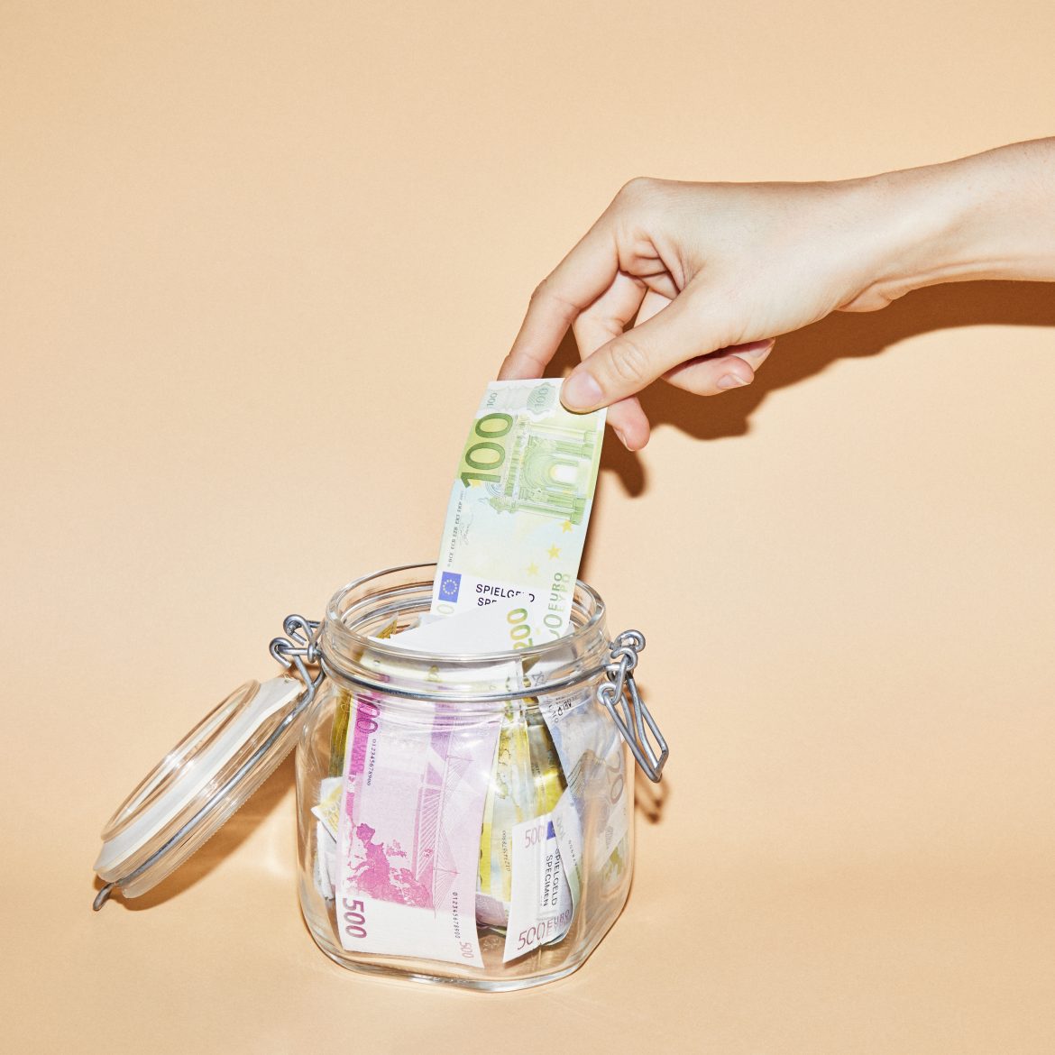 Hand pakt geld uit een spaarpot