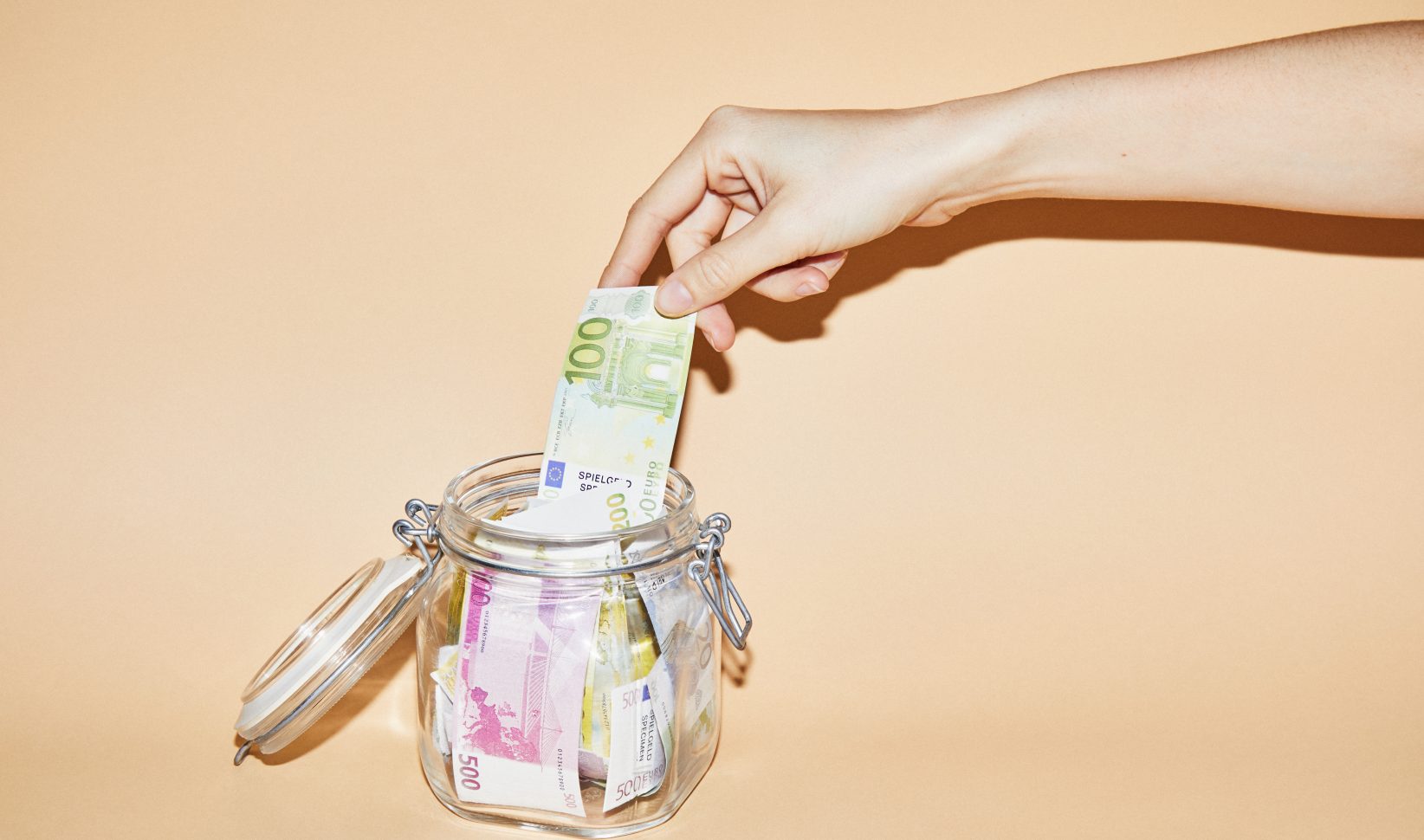Hand pakt geld uit een spaarpot