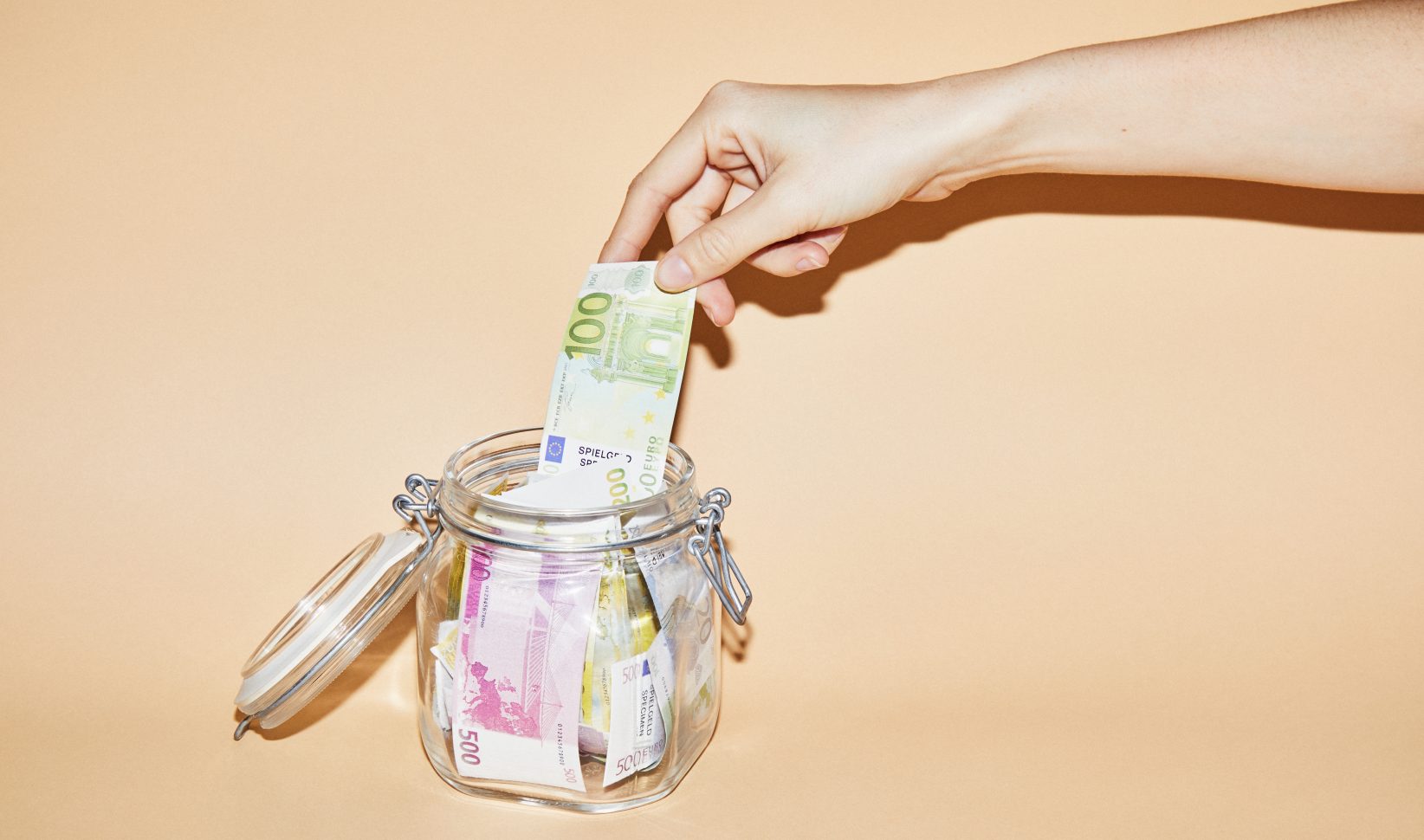 Hand pakt geld uit een spaarpot