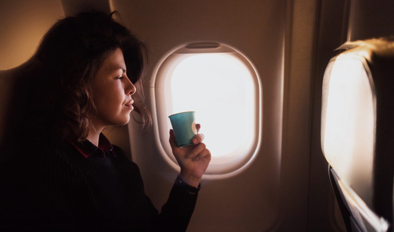 Vrouw drinkt koffie in het vliegtuig