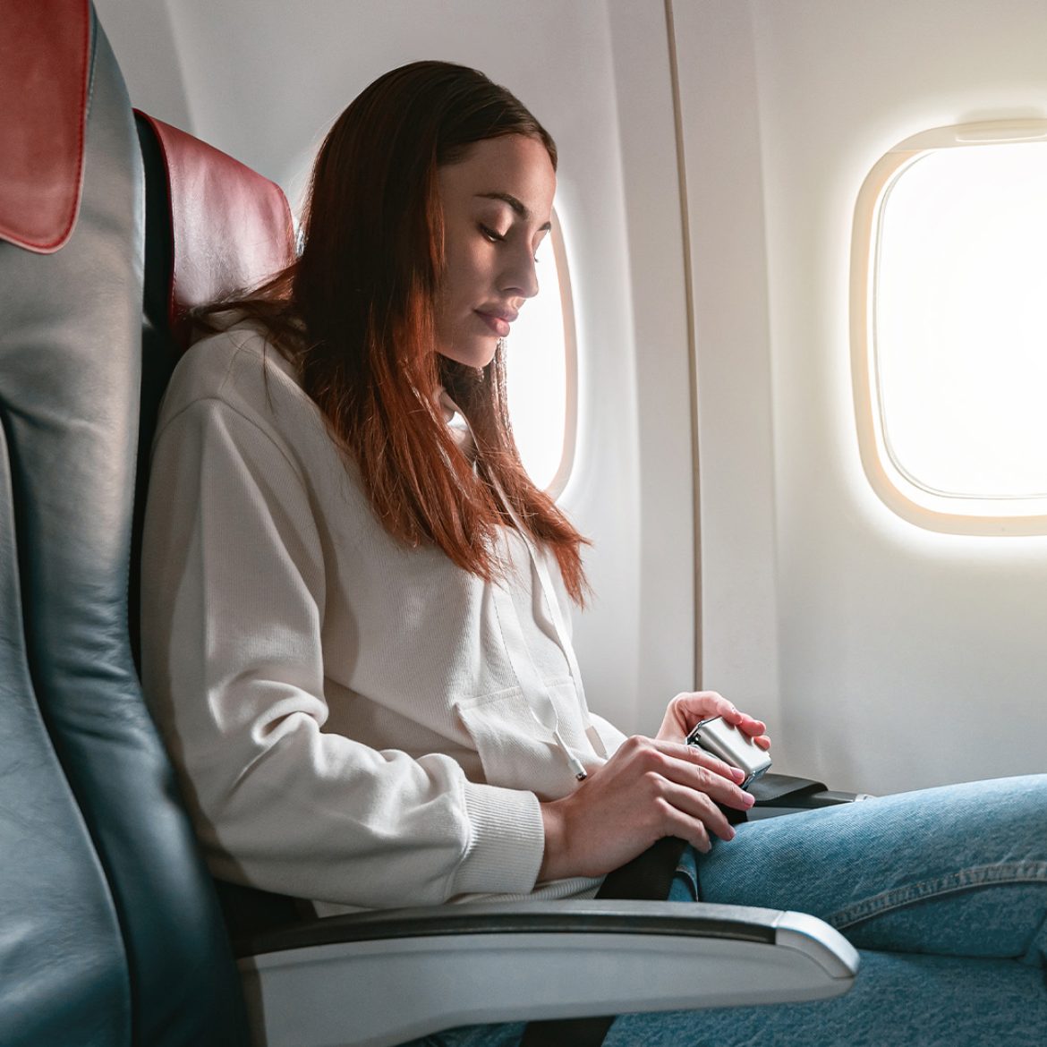 Vrouw zit in het vliegtuig met haar benen over elkaar | stewardess vieze plek