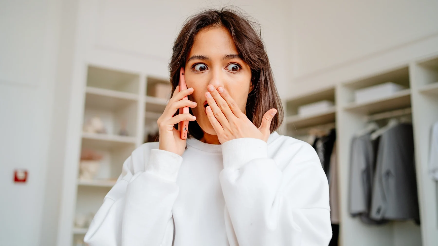 Vrouw telefoneert met een geschokte blik, na het zien van zweepjes in woonkamer van haar date
