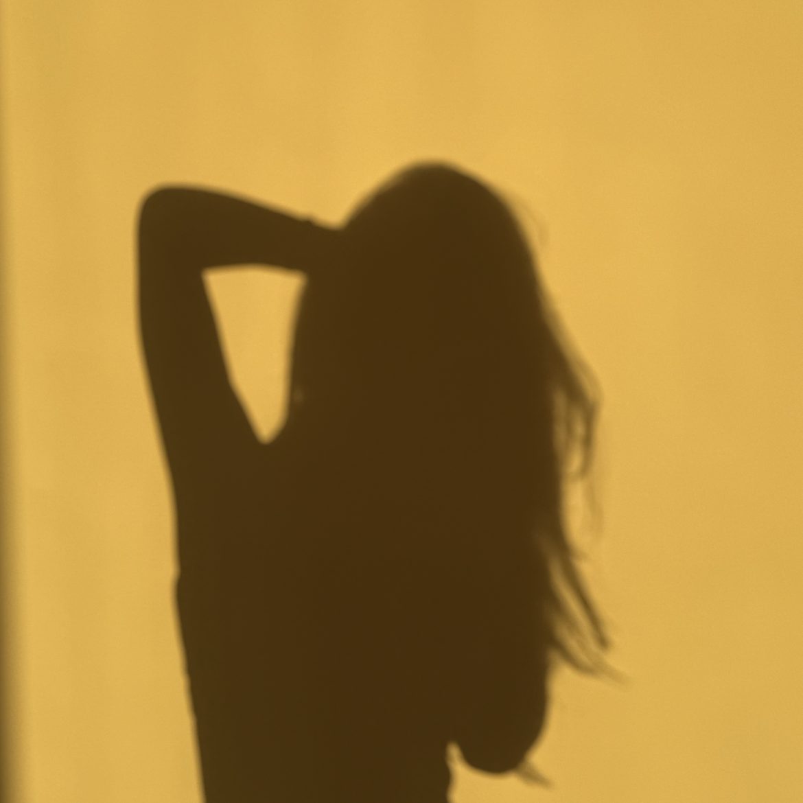 Schaduw van een vrouw op een gele muur