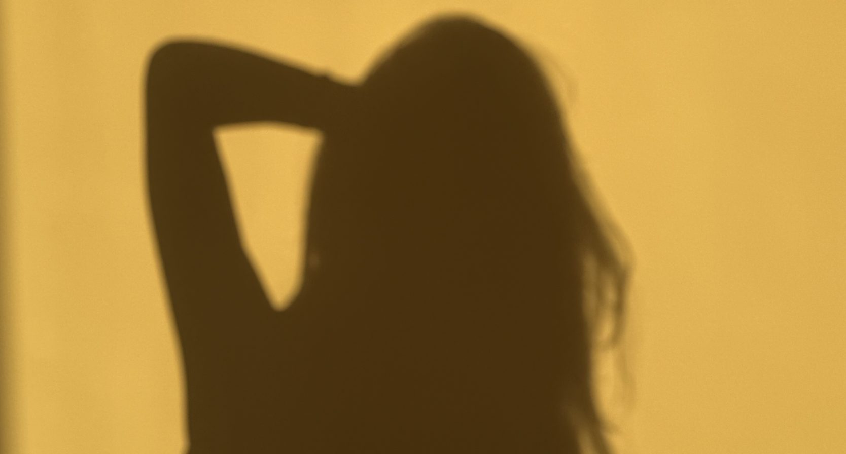 Schaduw van een vrouw op een gele muur