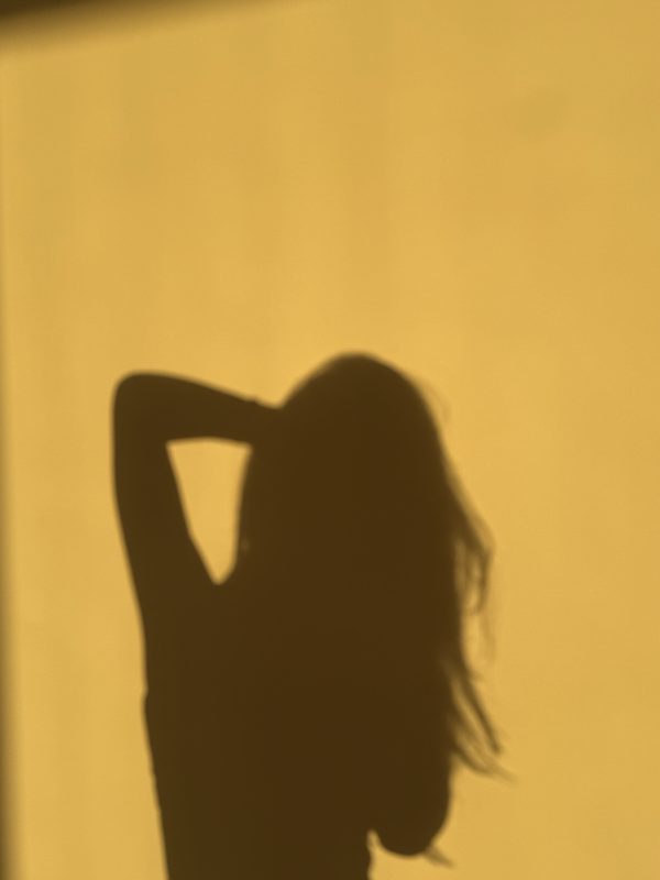 Schaduw van een vrouw op een gele muur