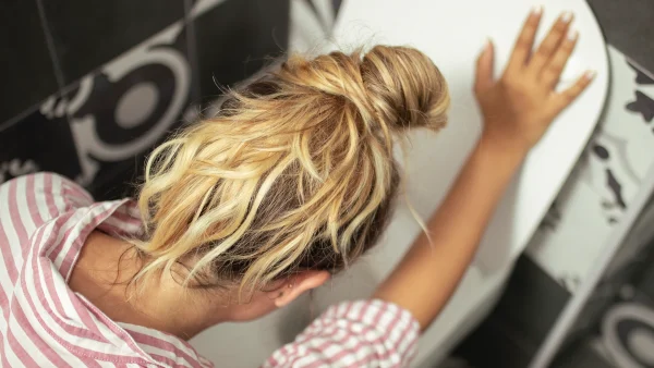 Blonde vrouw hangt boven het toilet