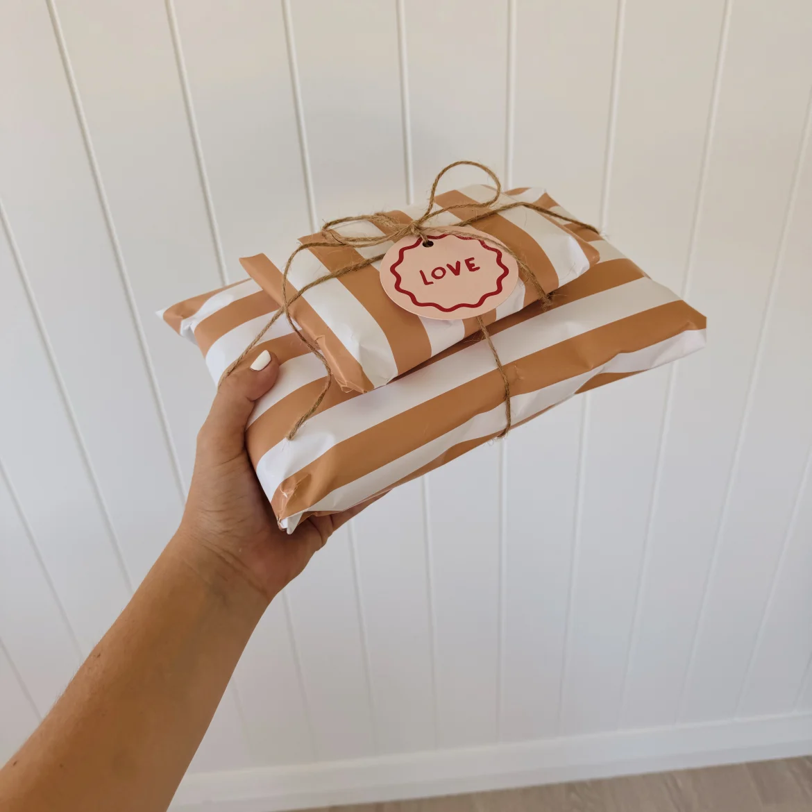 Vrouwenhand met cadeau ingepakt in gestreept papier