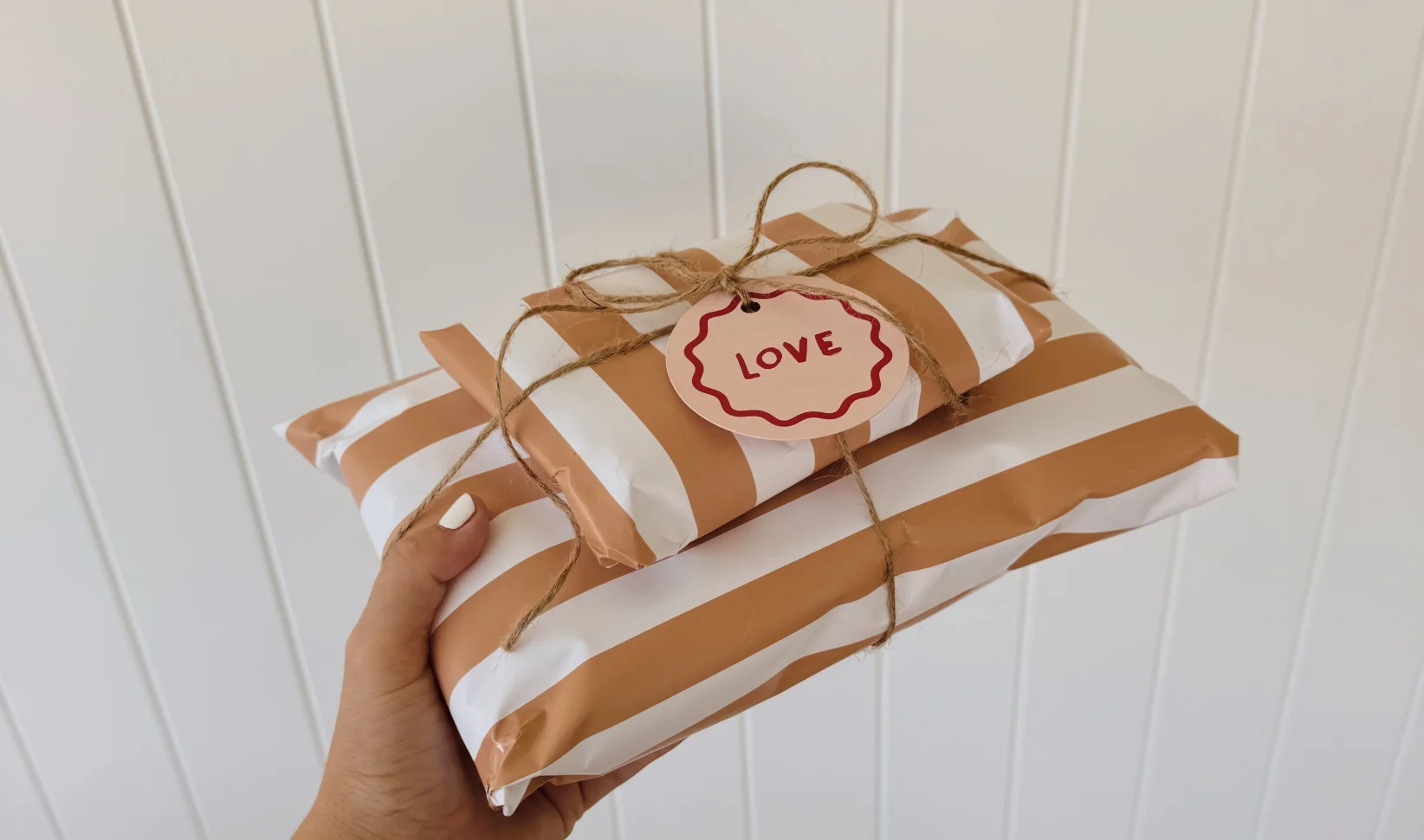 Vrouwenhand met cadeau ingepakt in gestreept papier