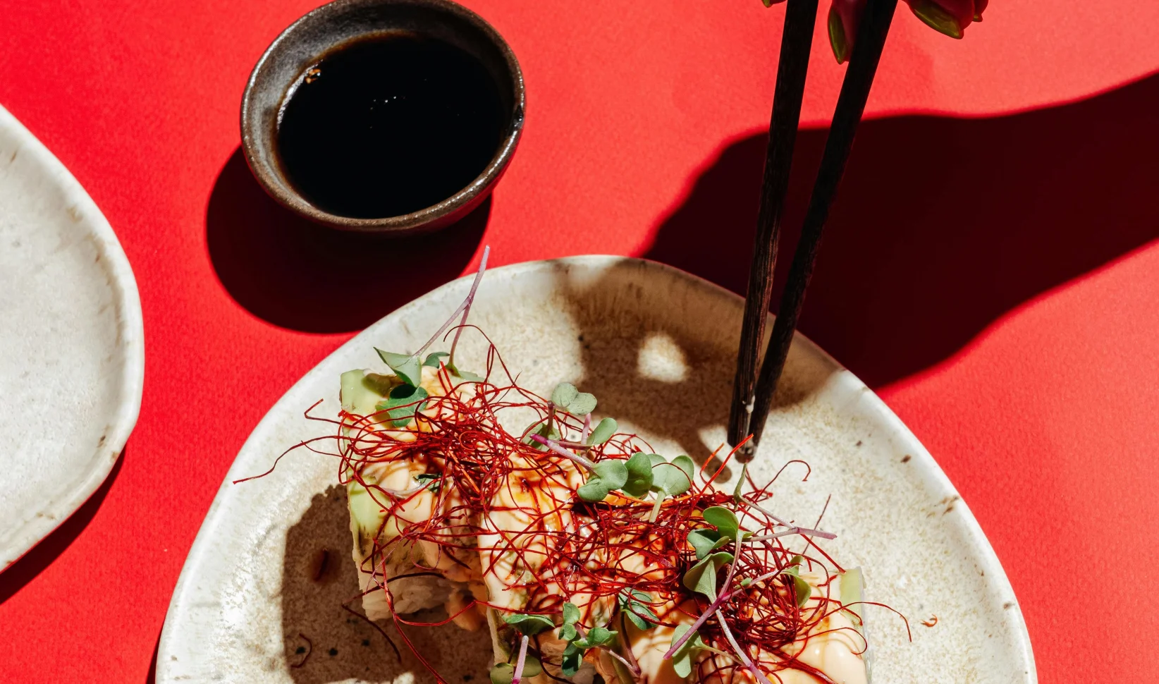 Vrouwenhand houdt stokjes vast en sushi op een rode achtergrond